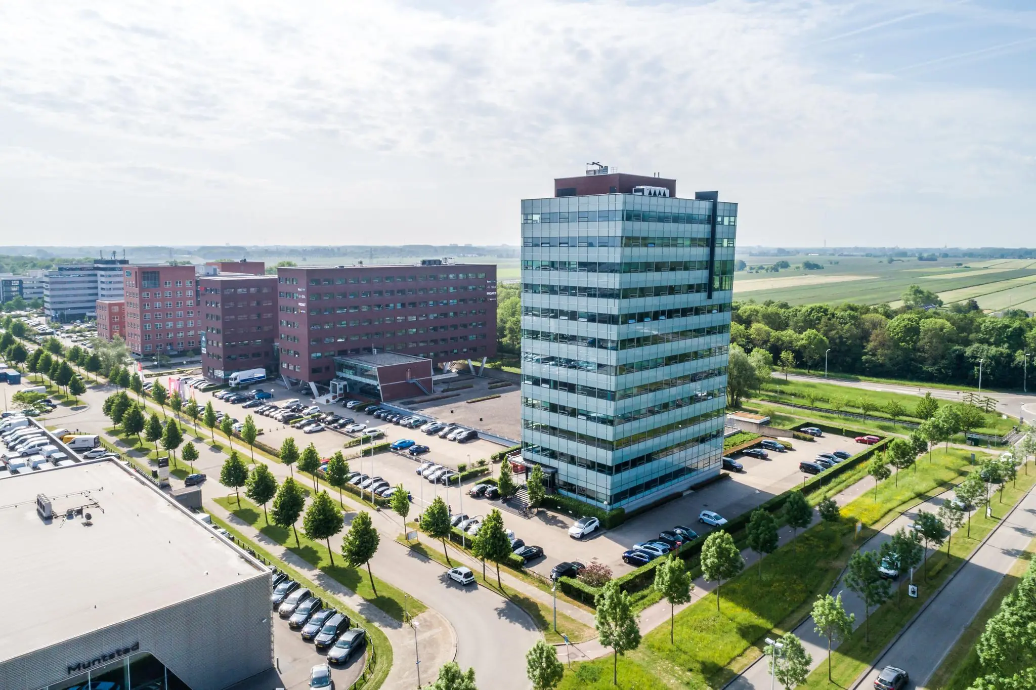 Luchtfoto van kantoorgebouwen aan de Rijnzathe in De Meern, omringd door parkeerplaatsen en groen landschap.