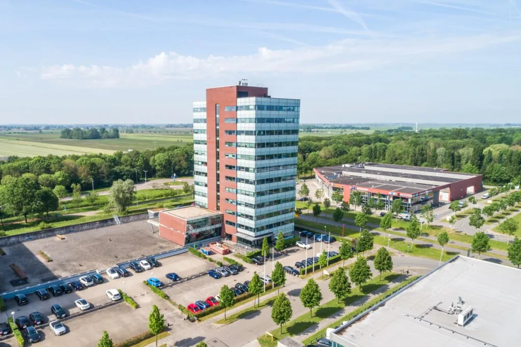 Luchtfoto van het kantoorgebouw Rijnzathe 6 in De Meern, omgeven door parkeerplaatsen, groen en andere bedrijfspanden.