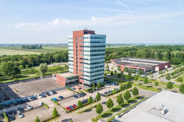 Luchtfoto van het kantoorgebouw Rijnzathe 6 in De Meern, omgeven door parkeerplaatsen, groen en andere bedrijfspanden.