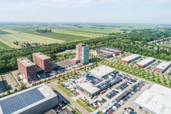 Luchtfoto van bedrijventerrein Rijnzathe met kantoorgebouwen, parkeerterreinen en omliggend groen landschap.