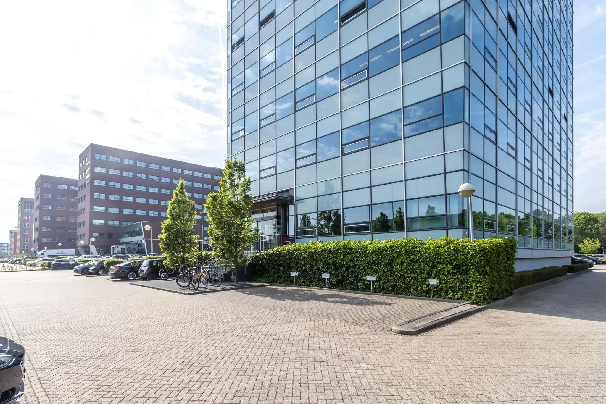 Moderne kantoorgebouwen aan de Rijnzathe met parkeerplaatsen en fietsenstalling op de voorgrond.