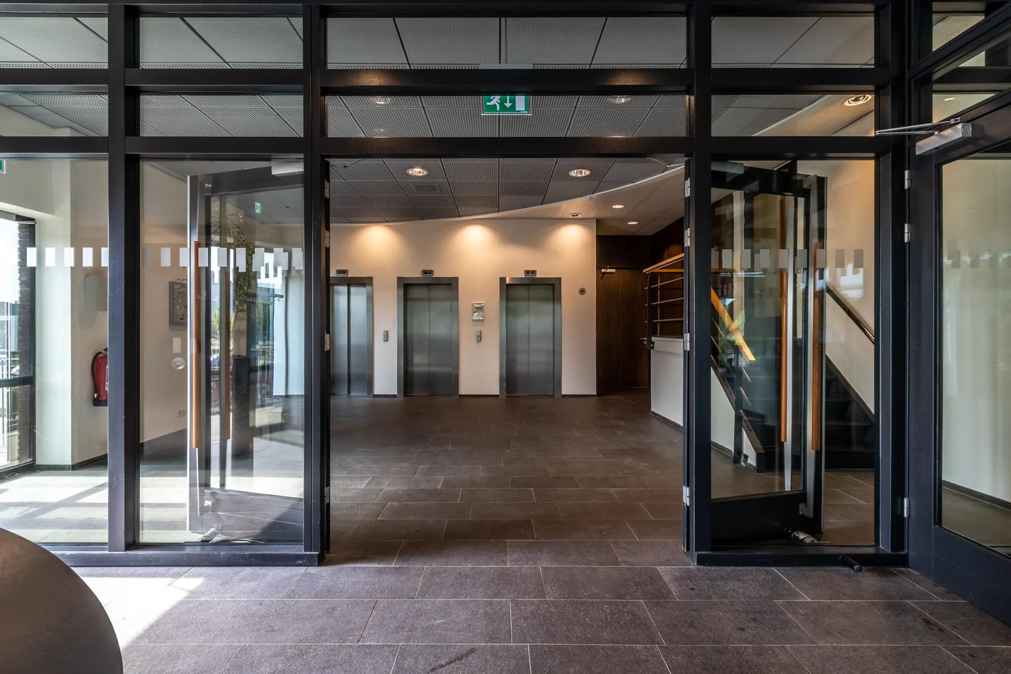 Moderne entreehal van kantoorgebouw Rijnzathe met drie liften en een trap.