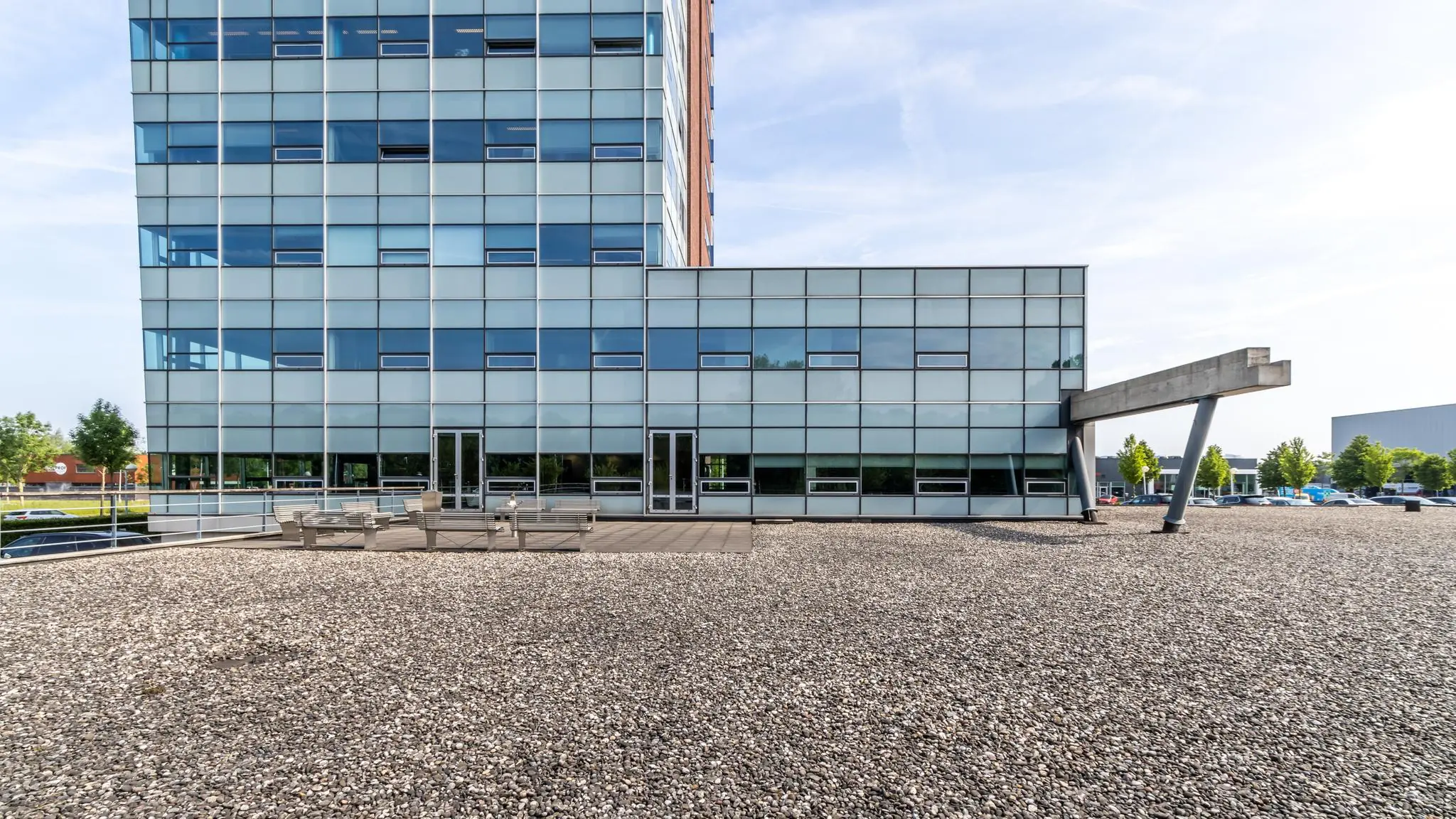 Modern kantoorgebouw aan de Rijnzathe met glazen gevel en dakterras met zitbanken.