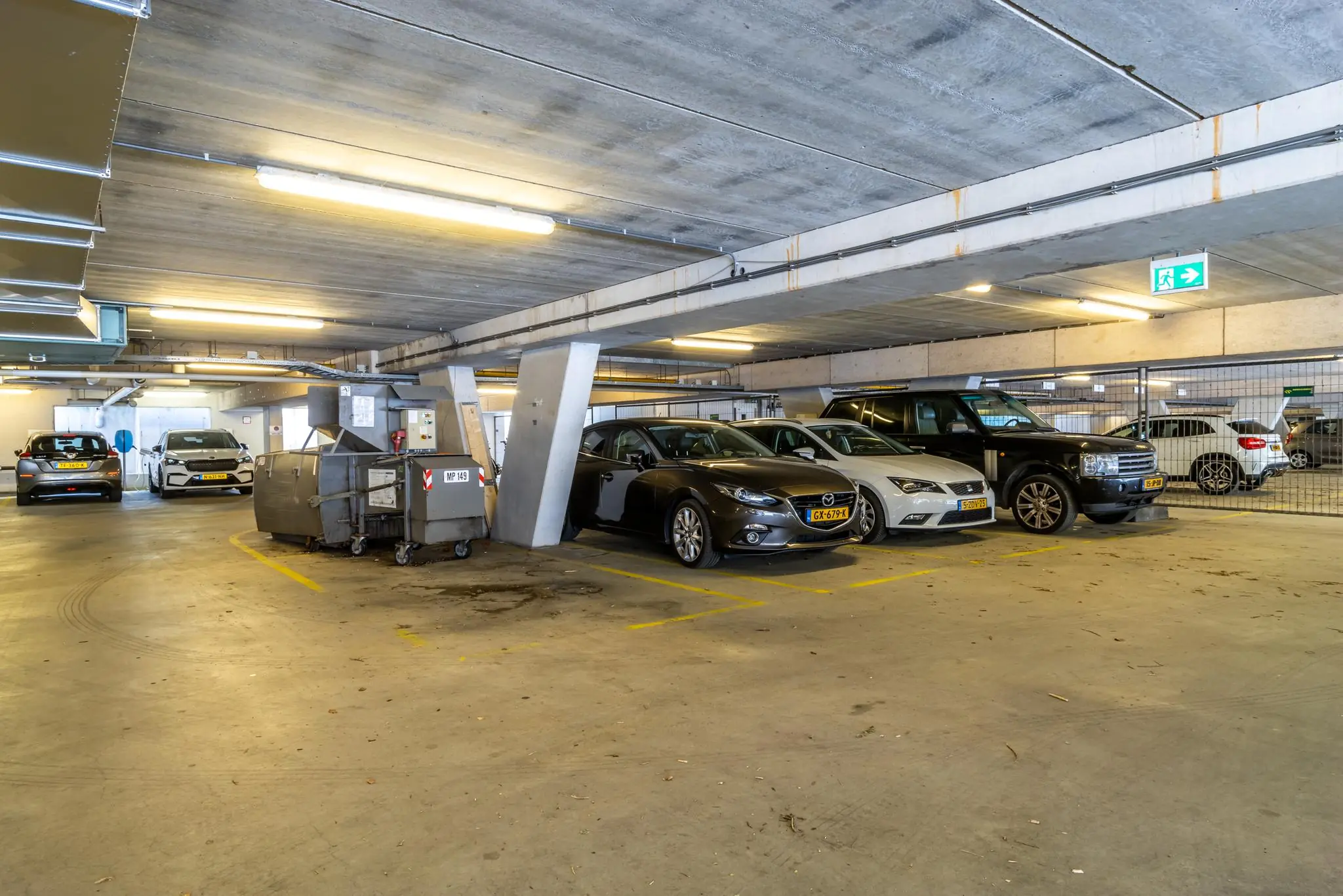 Parkeergarage Rijnzathe met geparkeerde auto's en een grote afvalcontainer.