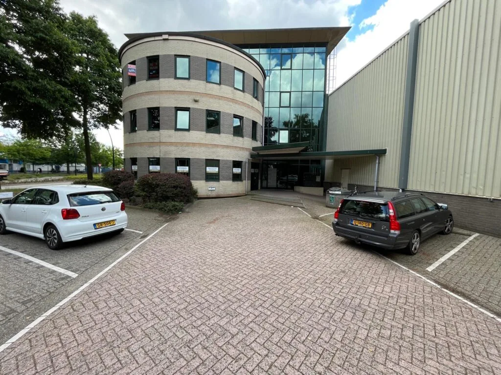 Kantoorpand aan de Koningsweg met te huur-borden en geparkeerde auto's op de parkeerplaats.