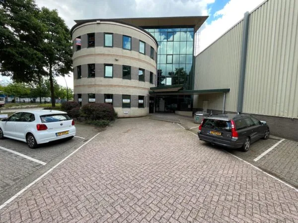 Kantoorpand aan de Koningsweg met te huur-borden en geparkeerde auto's op de parkeerplaats.