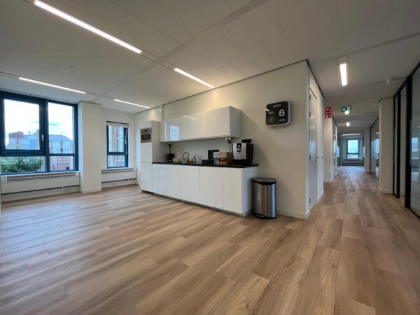 Moderne kantoorruimte met een open keuken en houten vloer in het gebouw aan het Kosterijland.
