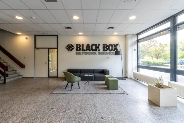 Moderne wachtruimte bij Black Box Network Services met zitmeubilair, een vloerkleed en grote ramen.
