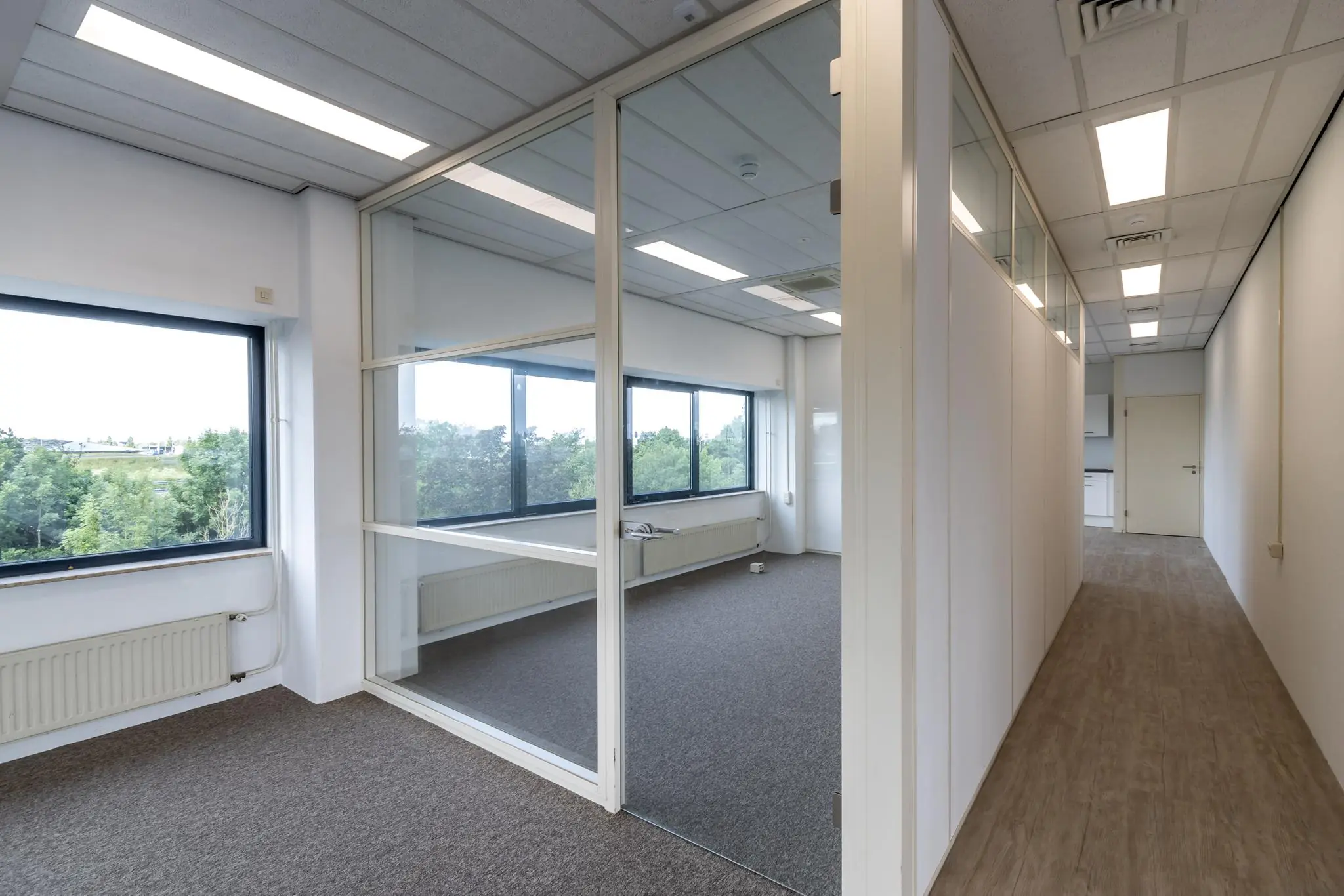 Modern kantoorinterieur aan de Zonnebaan met glazen vergaderruimte en uitzicht op groen.