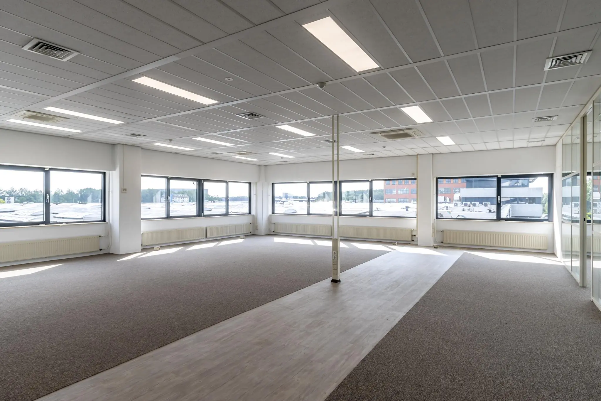 Lichte, lege kantoorruimte aan de Zonnebaan met grote ramen en systeemplafond.