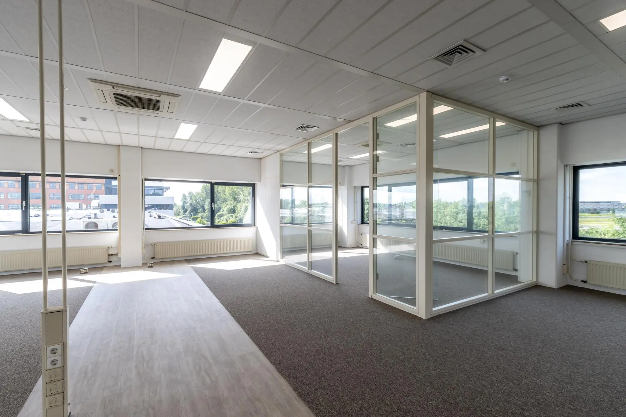 Licht en modern kantoorpand aan de Zonnebaan met glazen scheidingswanden en grote ramen.