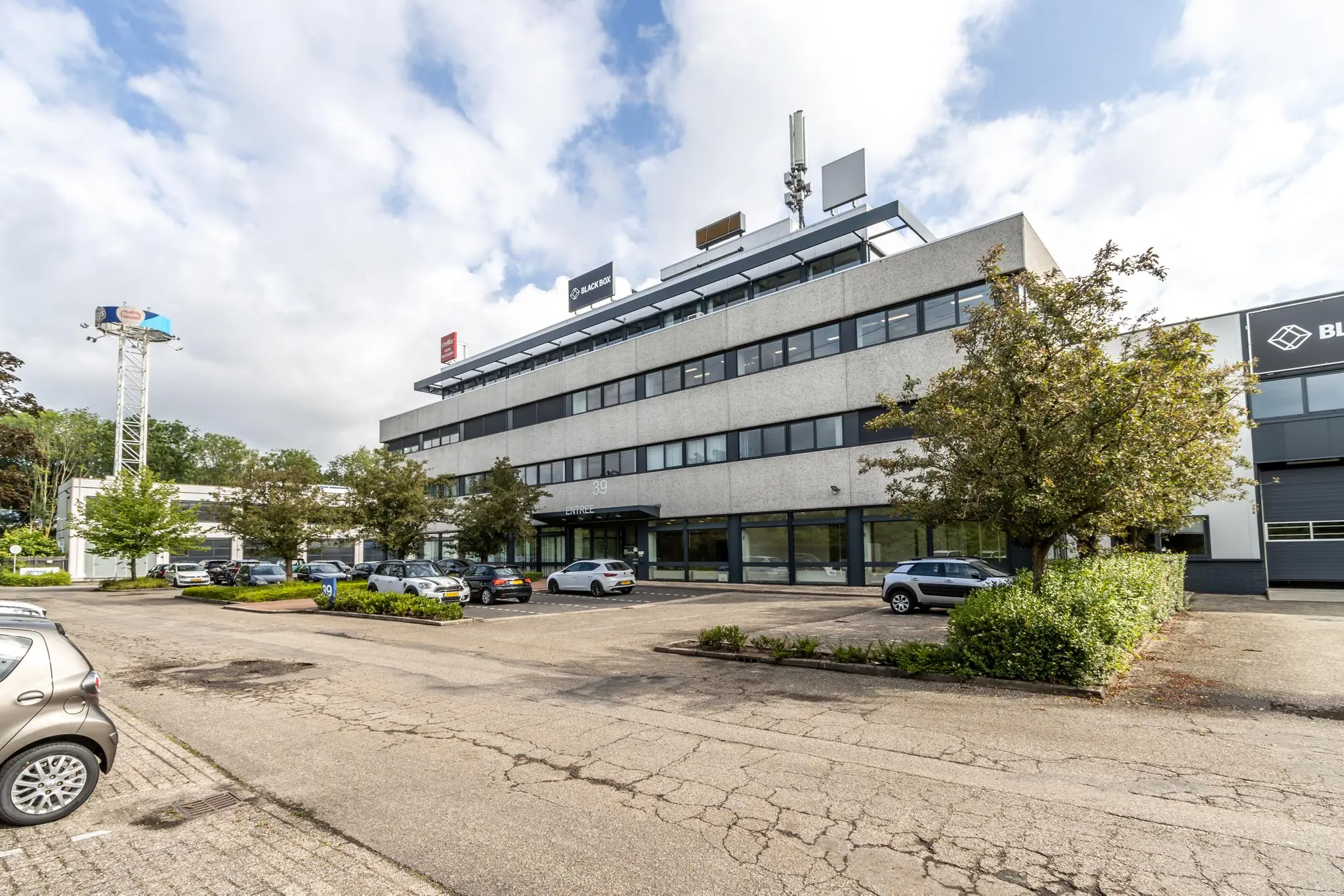 Kantoorpand aan de Zonnebaan 39 met parkeerplaatsen en omliggend groen.