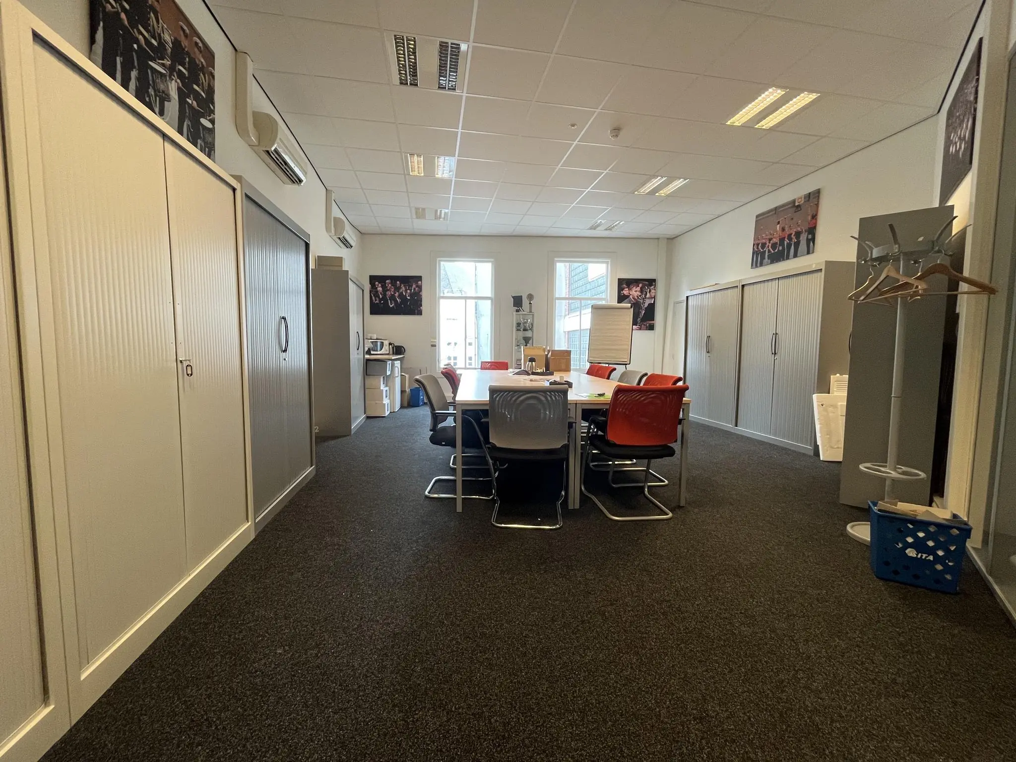 Vergaderruimte op de Ganzenmarkt met een lange tafel, diverse stoelen, kasten en wanddecoratie.