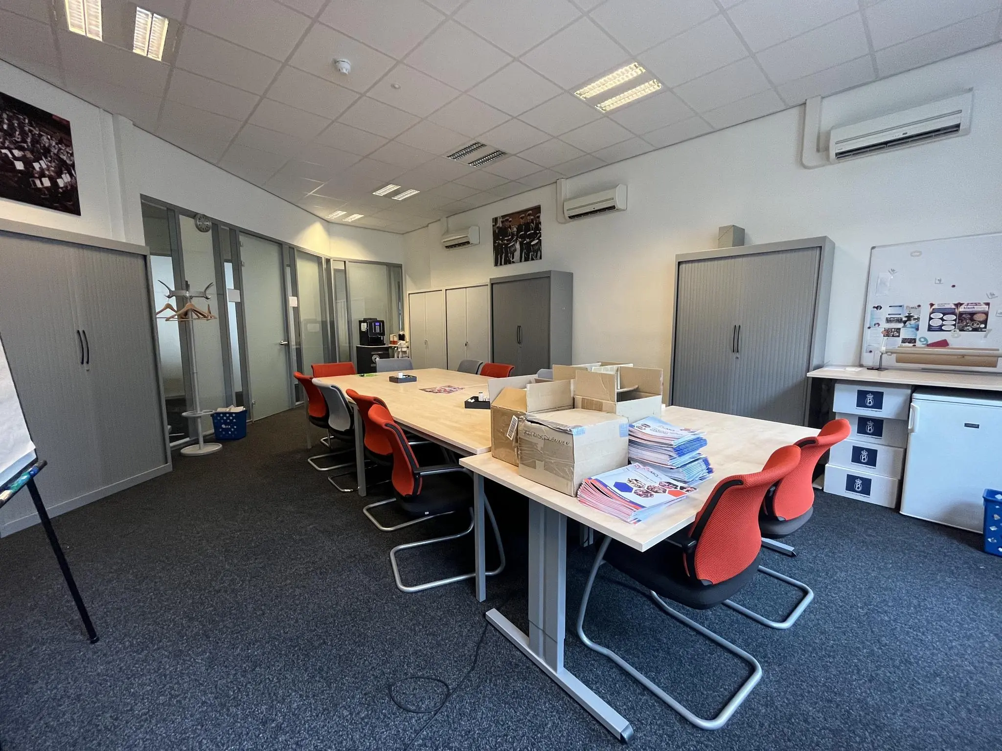 Vergaderruimte op de Ganzenmarkt met een lange tafel, rood-zwarte stoelen en stapels kleurrijke folders.