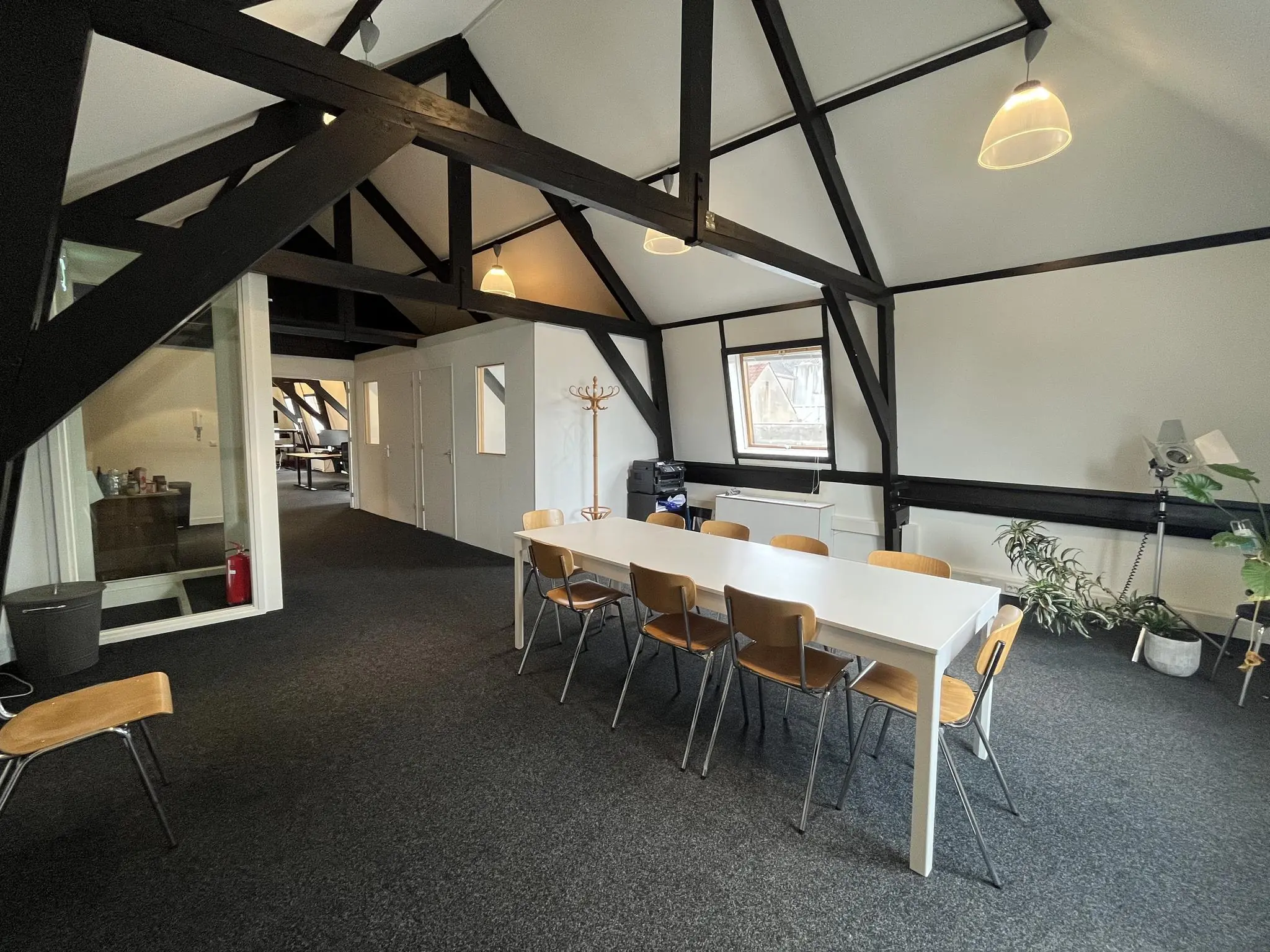Vergaderruimte in een modern kantoor met houten balken, een lange witte tafel en houten stoelen op de Ganzenmarkt.
