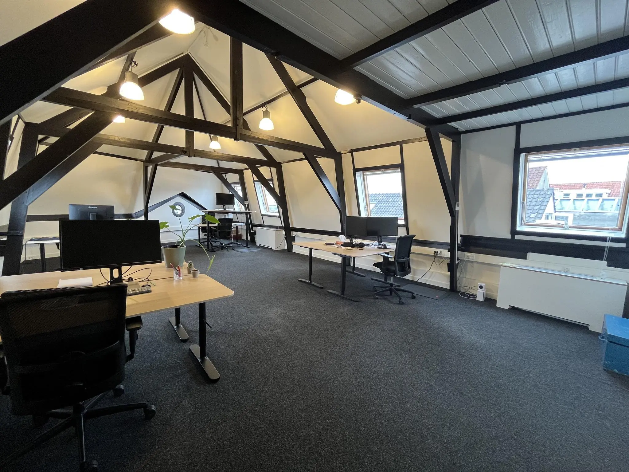 Modern kantoor met houten balken en schuine plafonds op een zolderverdieping aan de Ganzenmarkt.