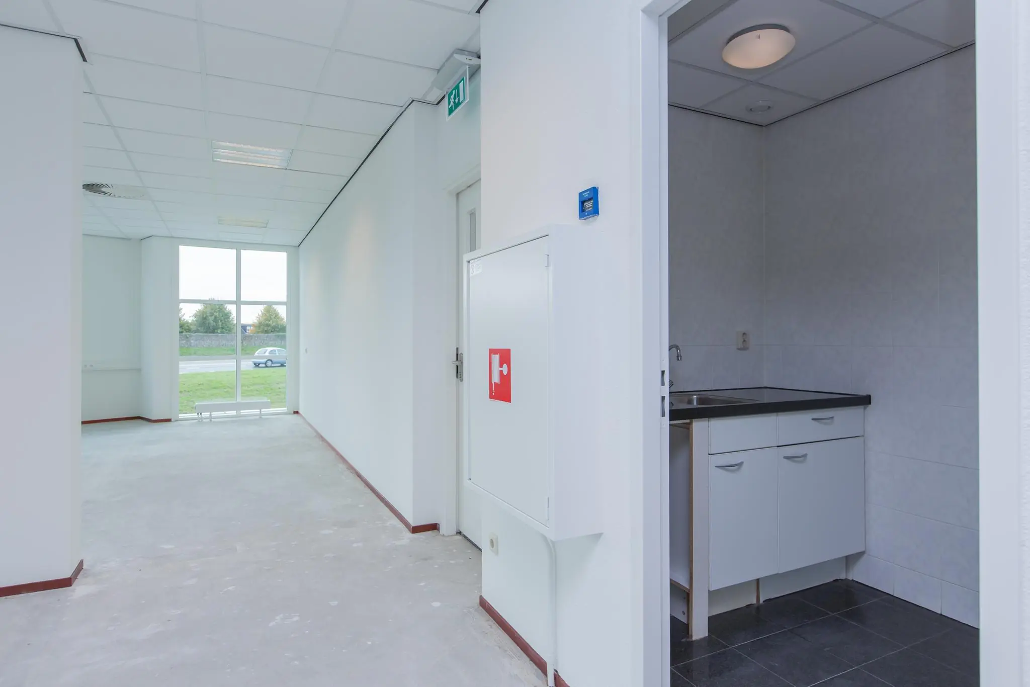 Lichte kantoorruimte aan het Rhijnspoor met kitchenette en uitzicht op groenstrook.