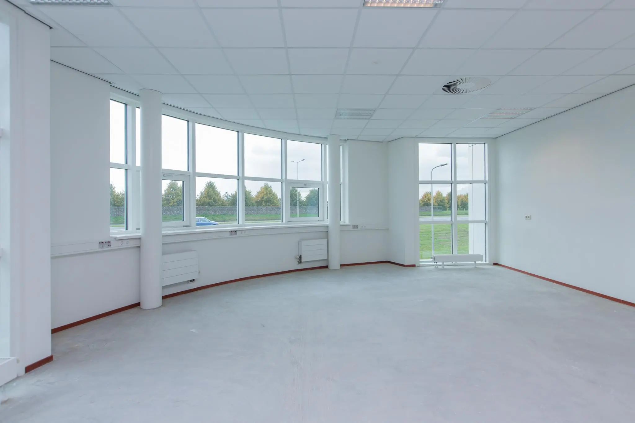 Lege, lichte kantoorruimte in Rhijnspoor met grote ramen en uitzicht op groen.
