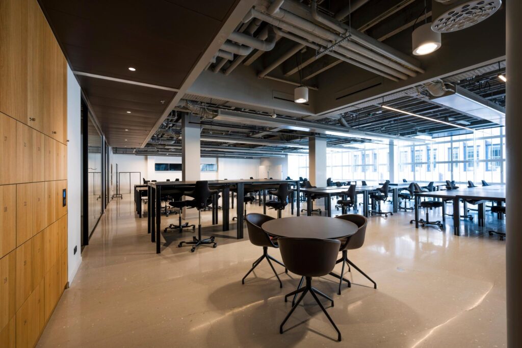 Moderne en ruime kantoorruimte aan het Rokin met bureaus, stoelen, lockers en grote ramen die natuurlijk licht binnenlaten.