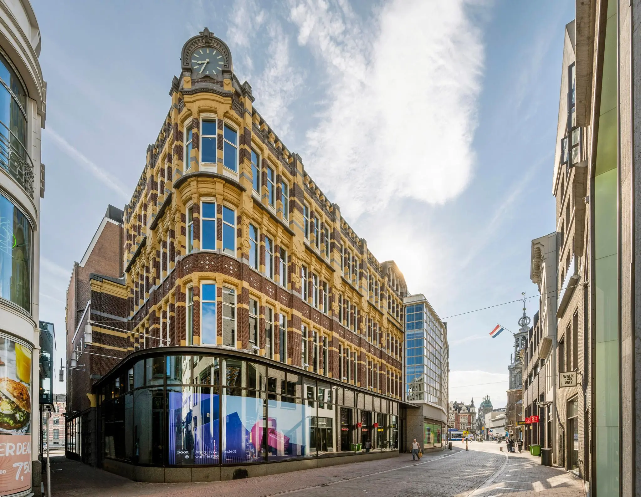 Historisch hoekpand aan het Rokin in Amsterdam met markante gevel en klok, gezien op een zonnige dag.