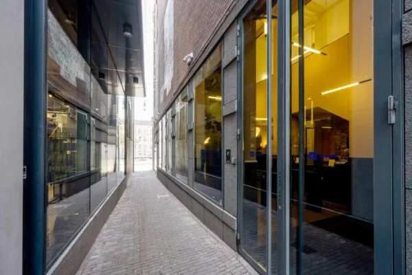 Smal steegje aan het Rokin in Amsterdam met moderne glazen gevels en een ingang van een kantoorruimte.