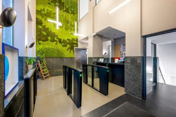 Moderne entreehal van een kantoorgebouw aan het Rokin met een groene moswand, beveiligingspoortjes en een receptiebalie.