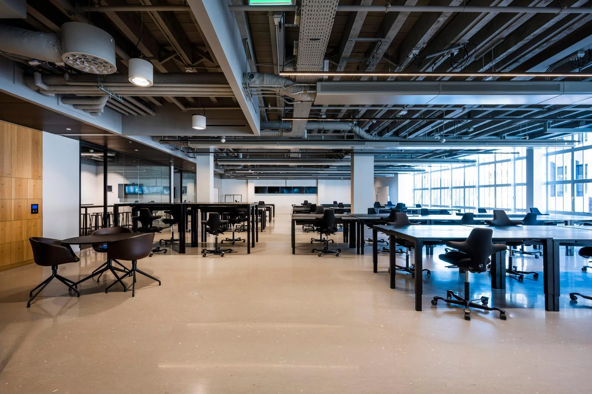 Moderne, open kantoorruimte aan het Rokin met zwarte bureaus, ergonomische stoelen en industriële plafonddetails.