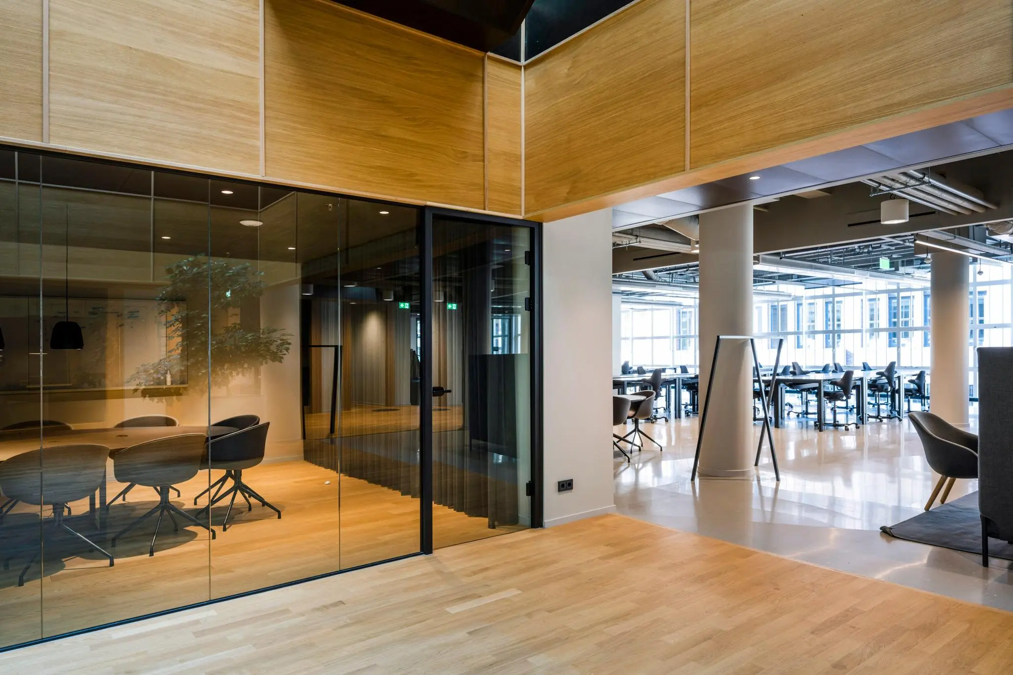 Moderne kantoorruimte aan het Rokin met glazen vergaderruimte, houten vloeren en open werkplekken.