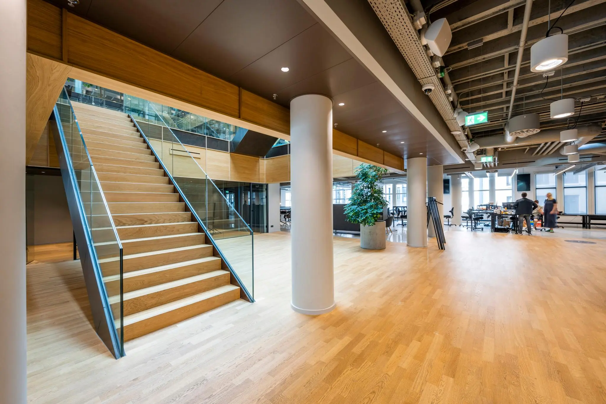 Moderne kantoorruimte aan het Rokin met houten trap, glazen balustrades en open werkplekken.