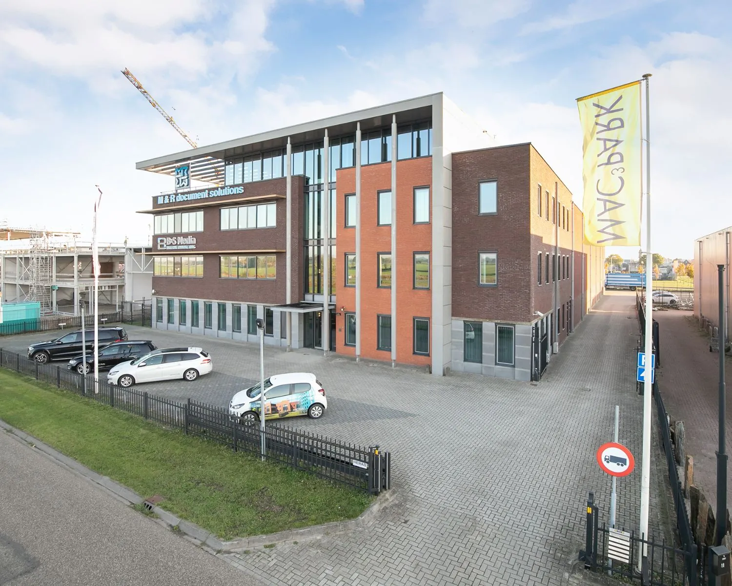 Modern kantoorgebouw aan de Carlsonstraat 13 in Kampen met parkeerplaatsen en bedrijfsnamen op de gevel.