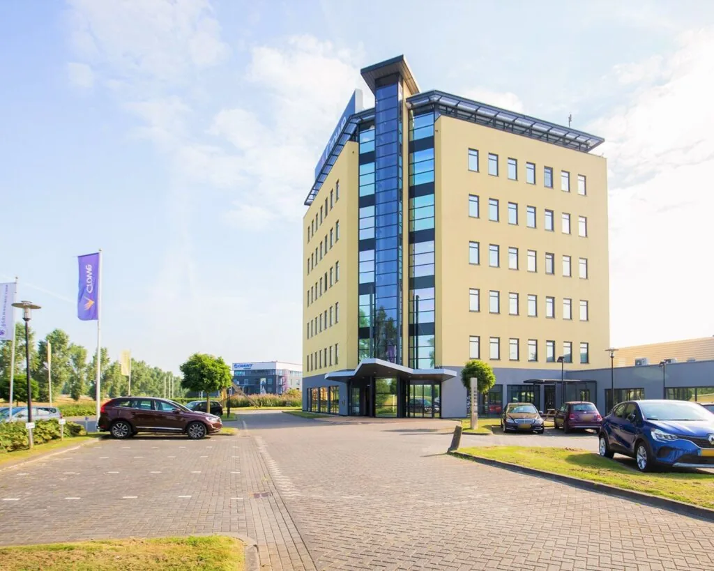Modern kantoorgebouw aan de Pascallaan 60-78 in Lelystad met parkeerplaatsen en vlaggen op het terrein.