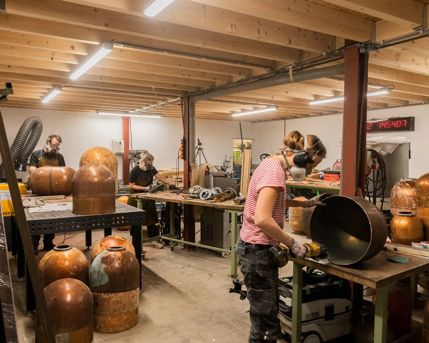 Drie mensen werken in een creatieve werkplaats in Steiger 24 in Almere aan koperen objecten.