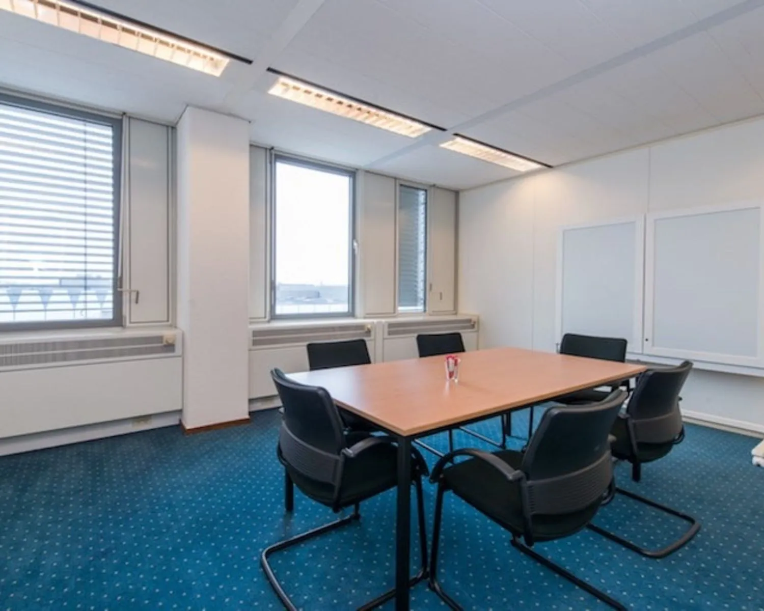 Vergaderruimte met zes stoelen en een rechthoekige tafel in een kantoor aan de Gaetano Martinolaan 75-95 in Maastricht.