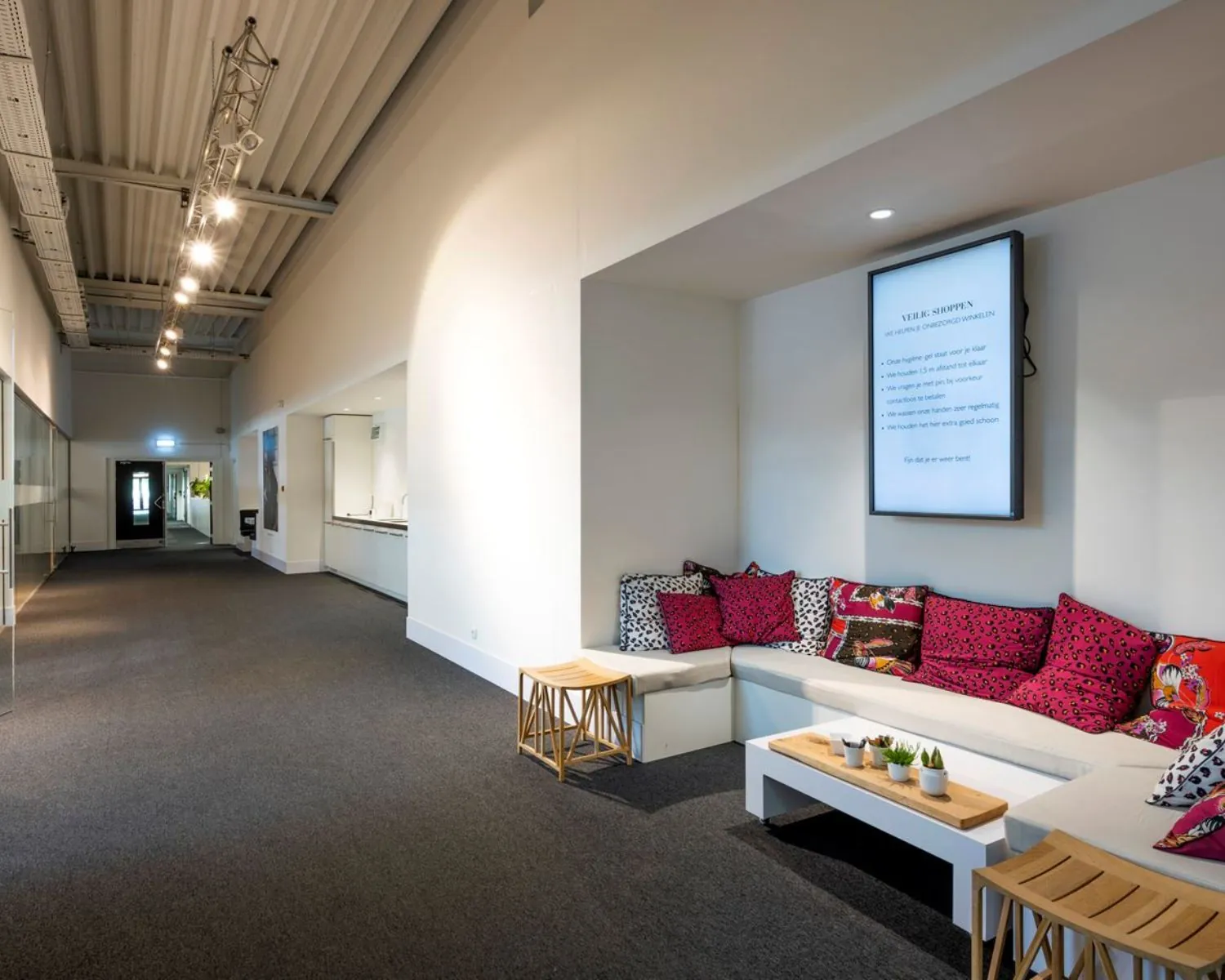 Moderne wachtruimte in kantoorruimte aan Stammerhove 1 in Diemen met kleurrijke kussens, een zithoek en een informatiescherm aan de muur.