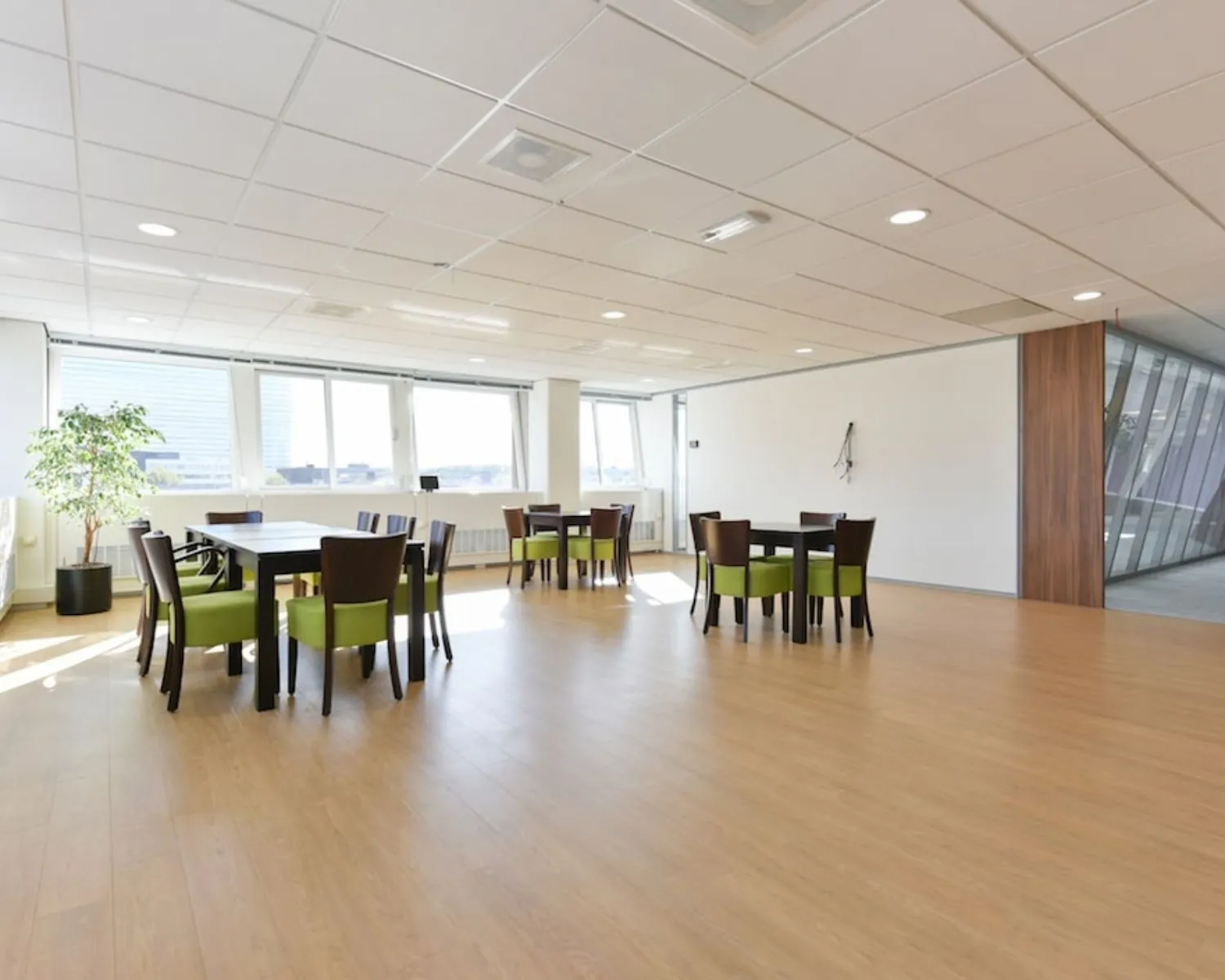 Moderne, lichte kantoorruimte aan de Treubstraat 1 in Rijswijk met houten vloer, vergadertafels en grote ramen.