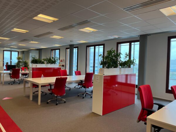 Moderne kantoorruimte aan de Hondiuslaan met rode stoelen, witte bureaus en grote ramen.