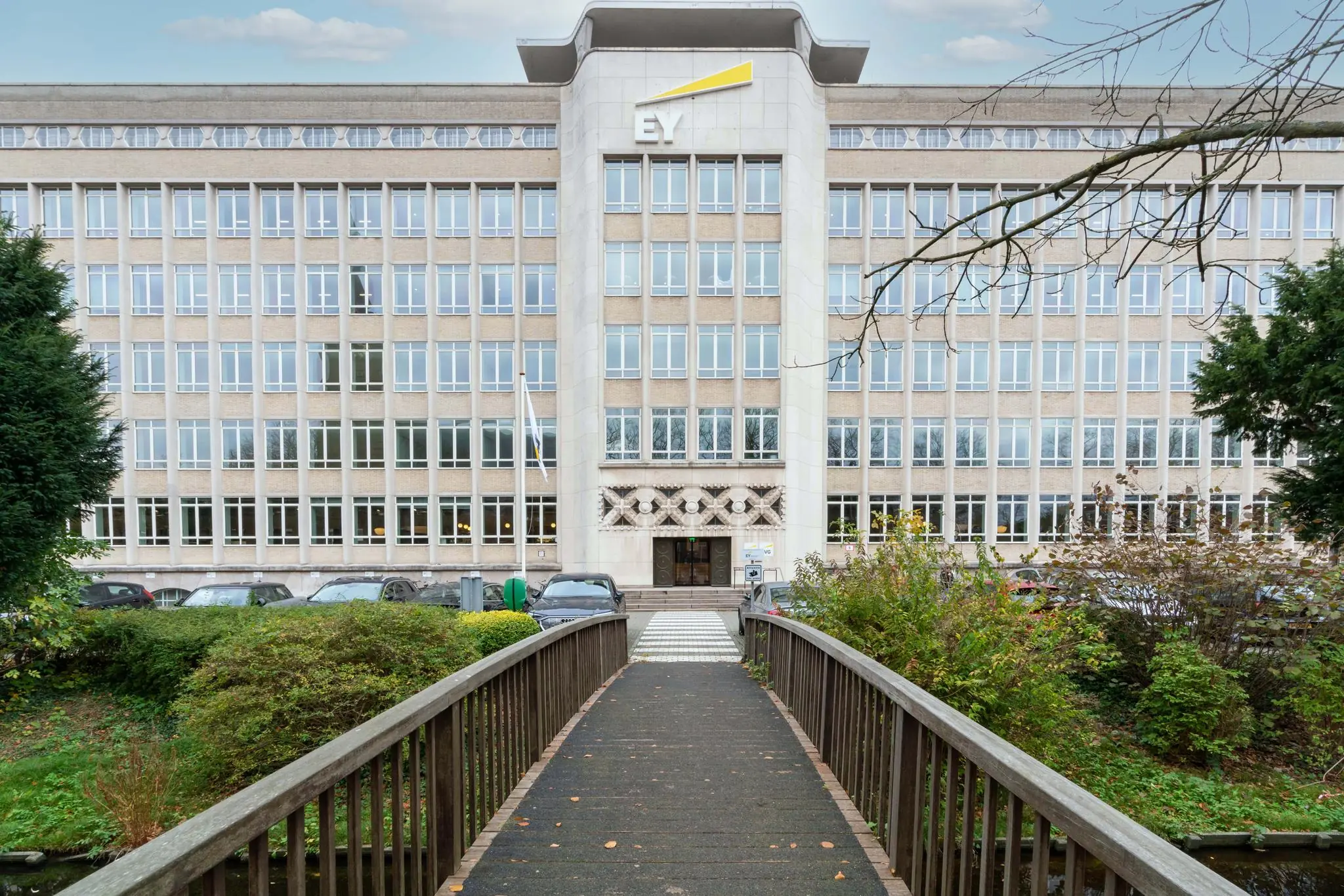 Voorgevel van het EY-kantoorgebouw aan de Wassenaarseweg, gezien vanaf een voetgangersbrug over een groenstrook.