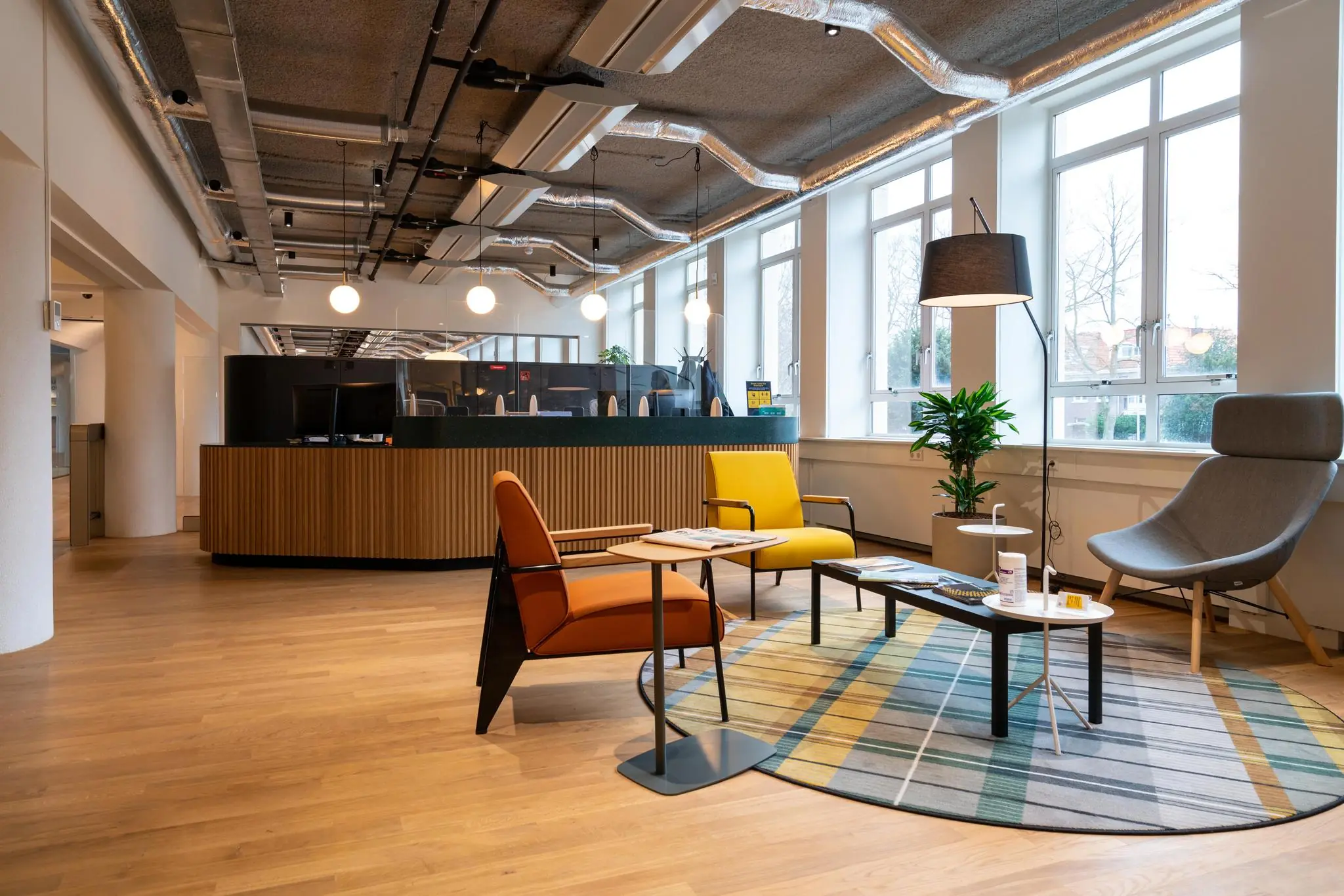 Moderne wachtruimte met kleurrijke stoelen, een ronde vloerkleed en een houten receptiebalie aan de Wassenaarseweg.