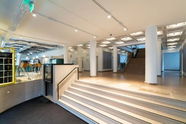 Moderne en lichte entreehal met brede trap, lift en uitzicht op een zithoek aan de Wassenaarseweg.