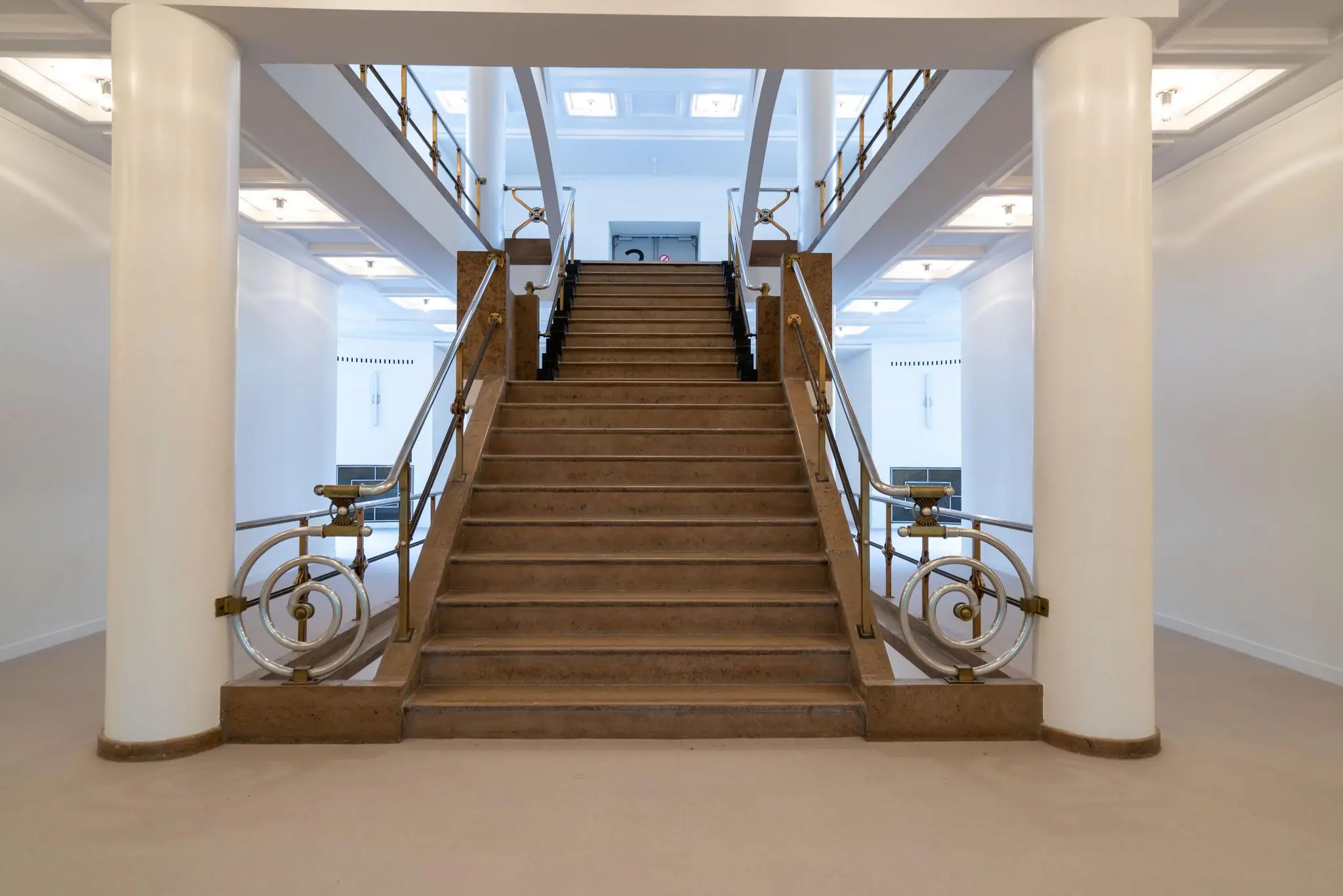 Symmetrische monumentale trap met sierlijke leuningen in een licht en modern interieur aan de Wassenaarseweg.