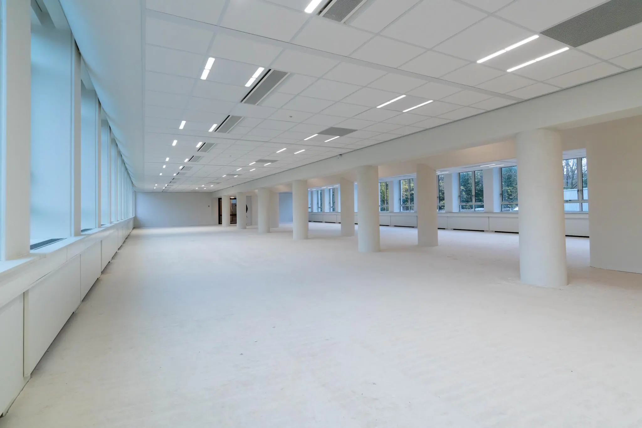 Lichte, leegstaande kantoorruimte aan de Wassenaarseweg met grote ramen en witte zuilen.