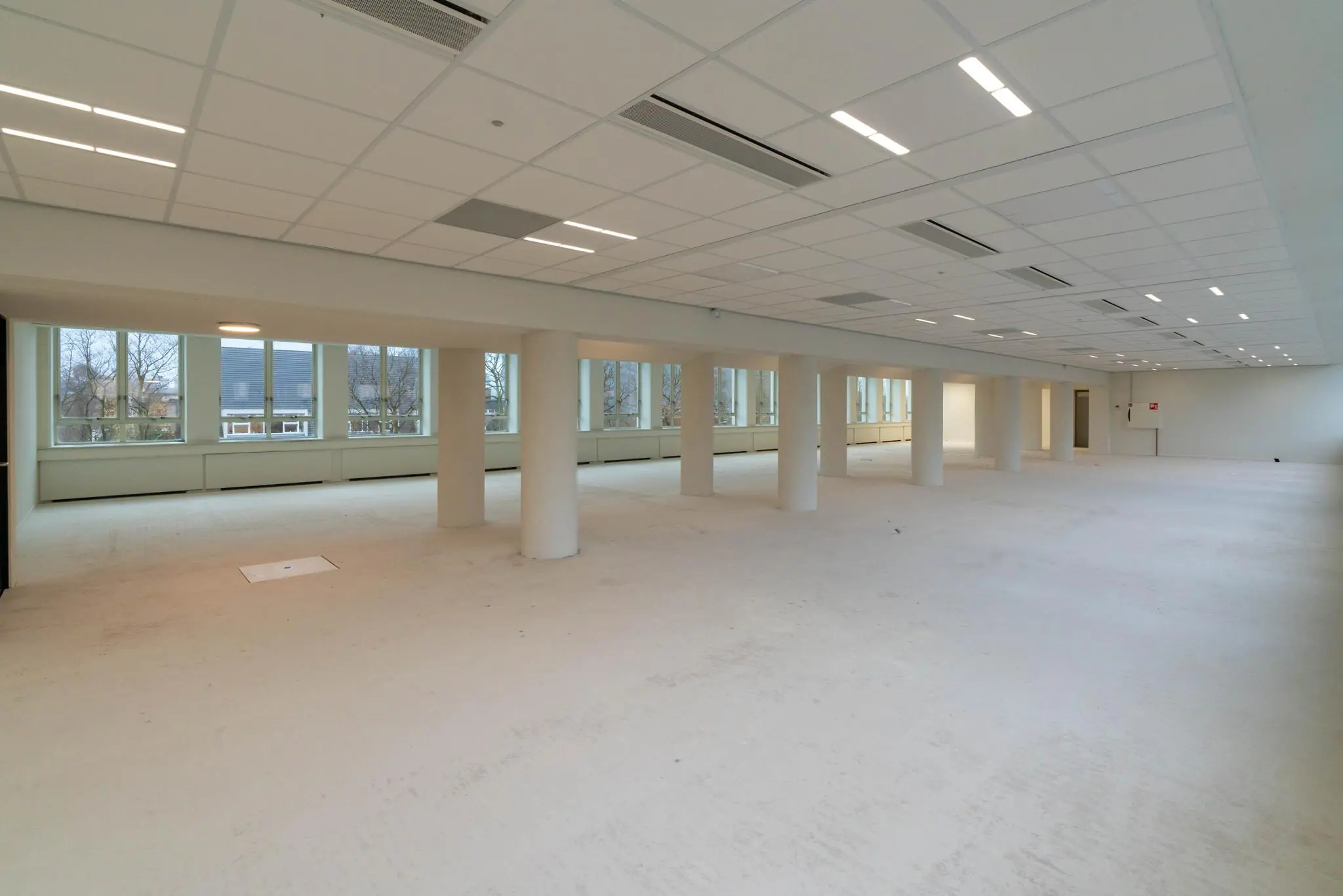 Licht en ruim leeg kantoorpand aan de Wassenaarseweg met grote ramen en witte pilaren.