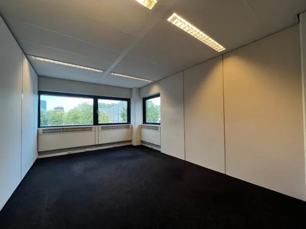 Lege kantoorruimte aan de Vreeswijksestraatweg met grote ramen en uitzicht op bomen en gebouwen.