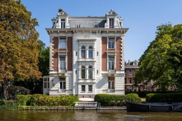 Monumentaal herenhuis aan de Weteringschans in Amsterdam, gelegen aan het water en omgeven door groen.