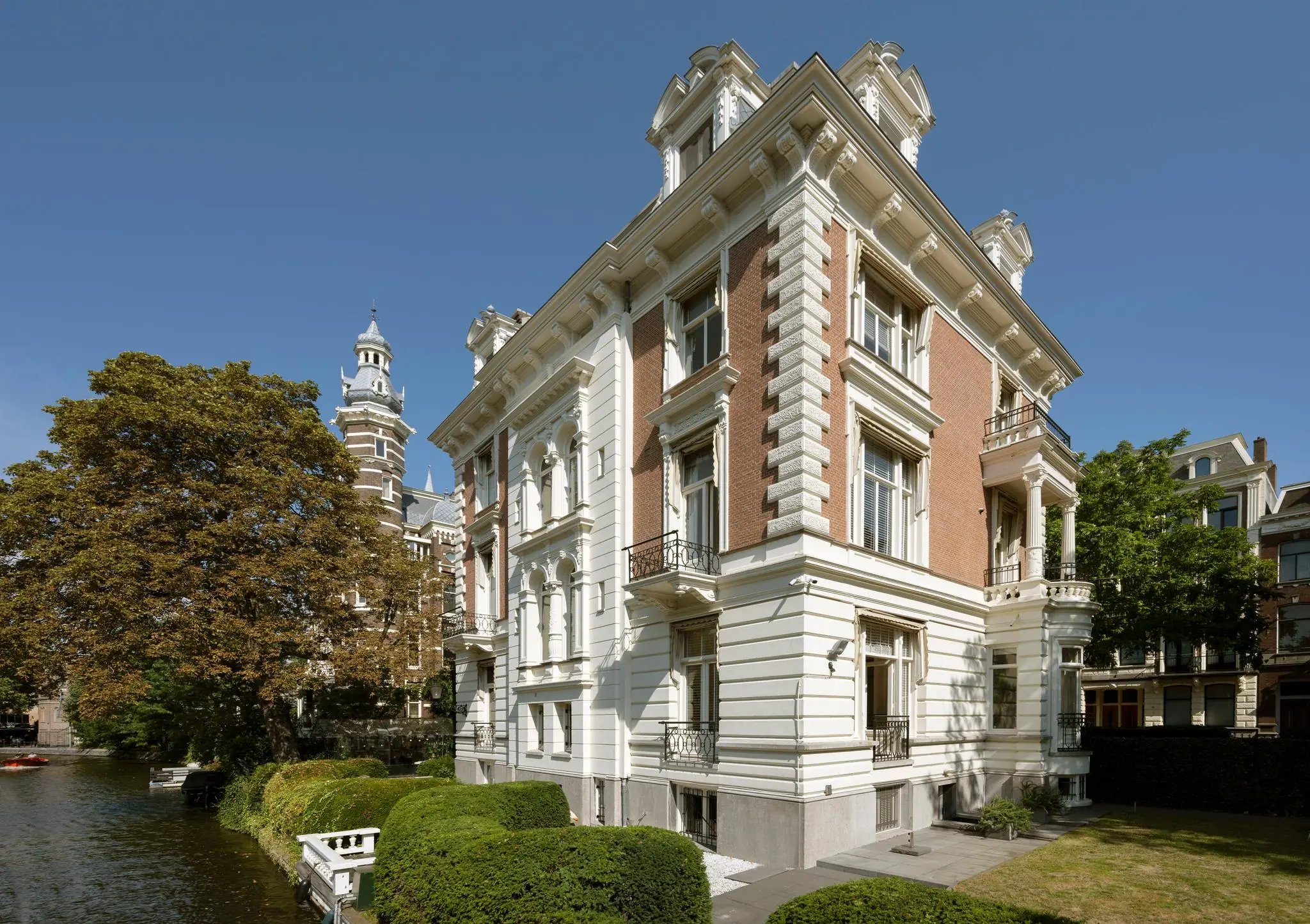 Klassiek herenhuis aan de Weteringschans in Amsterdam met uitzicht op een gracht en een historische toren op de achtergrond.