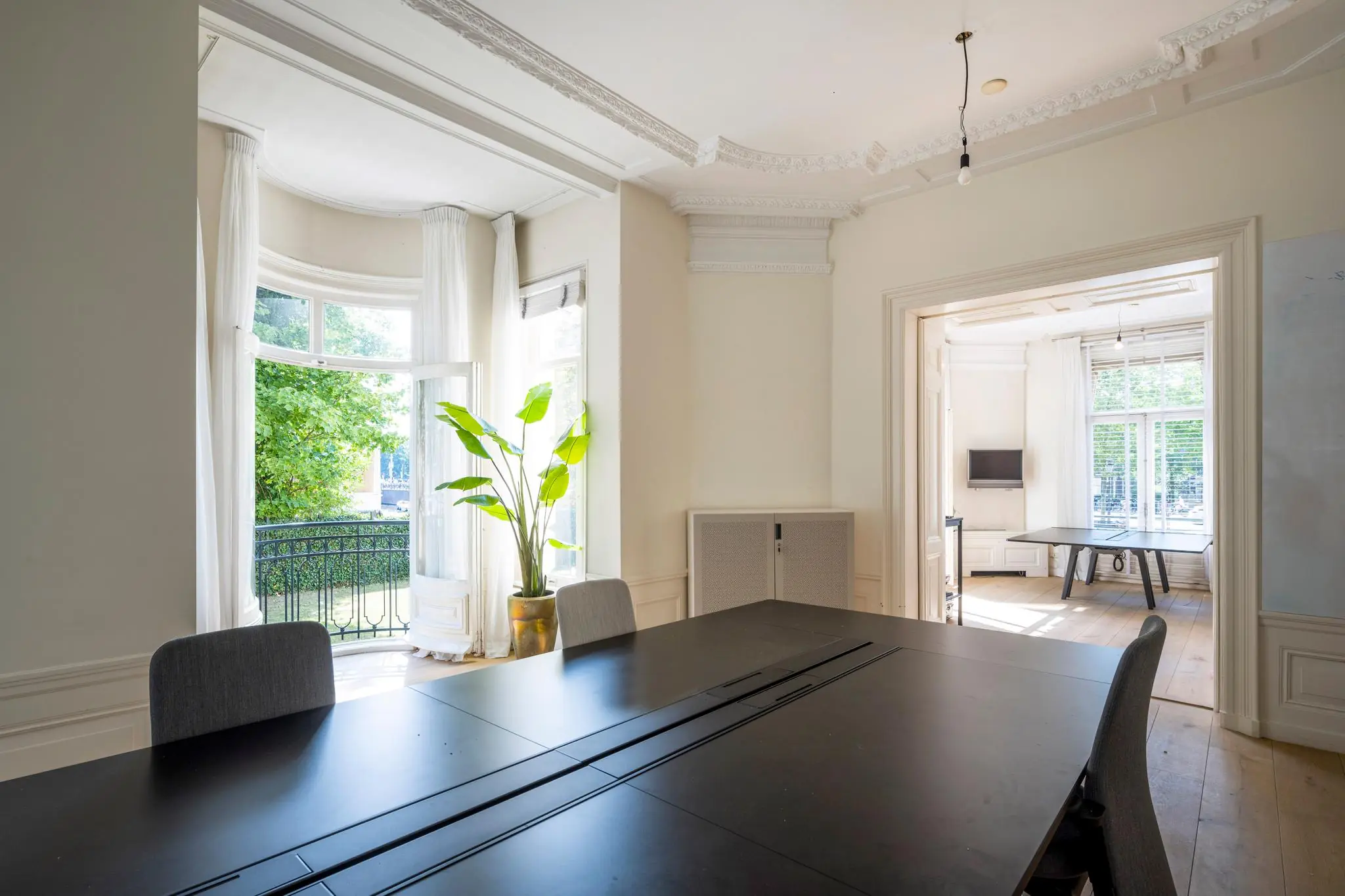 Lichte vergaderruimte aan de Weteringschans met hoge plafonds, klassieke details en uitzicht op een groen balkon.