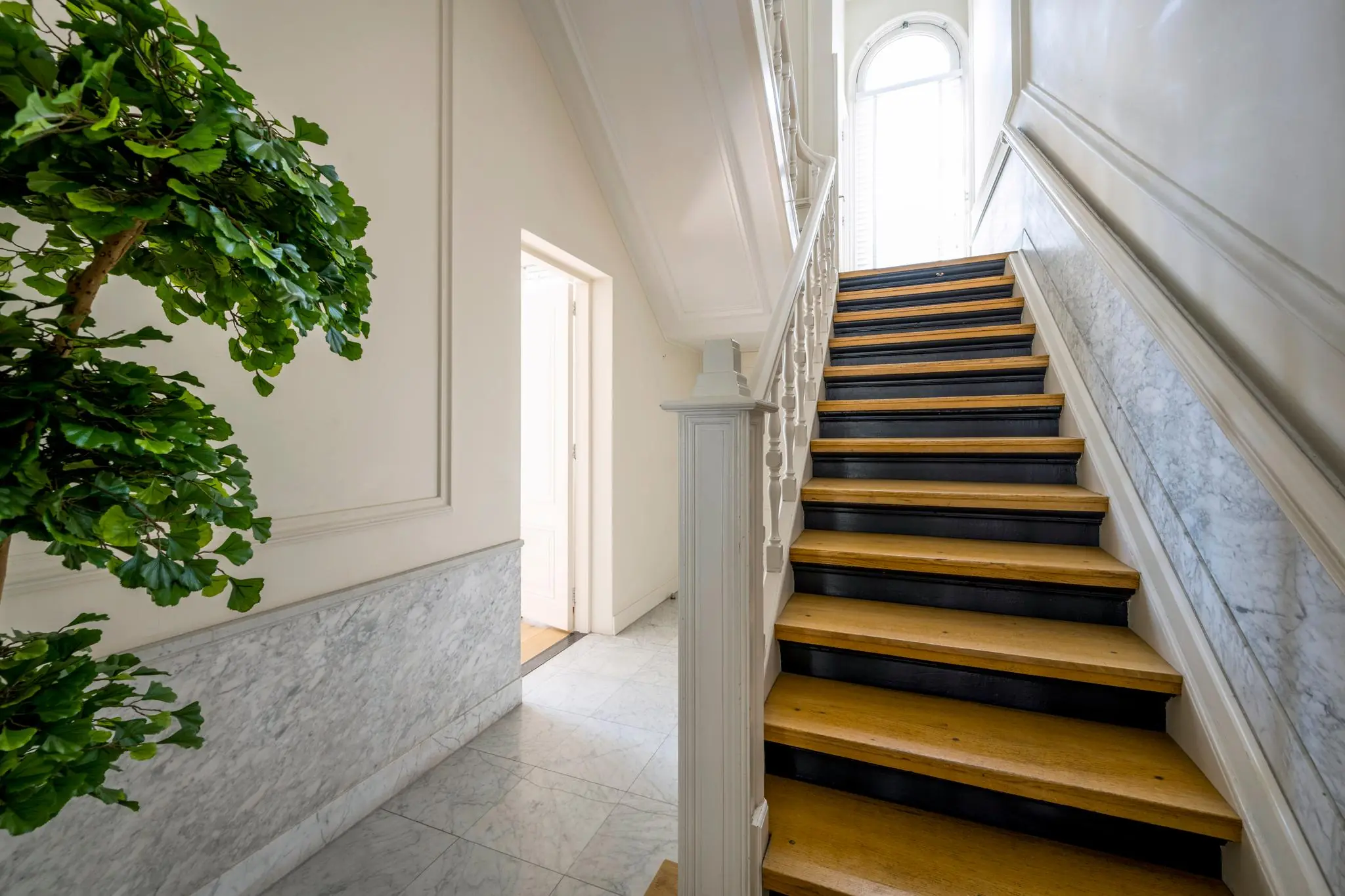 Trap met houten treden en witte leuning in een klassiek herenhuis aan de Weteringschans.