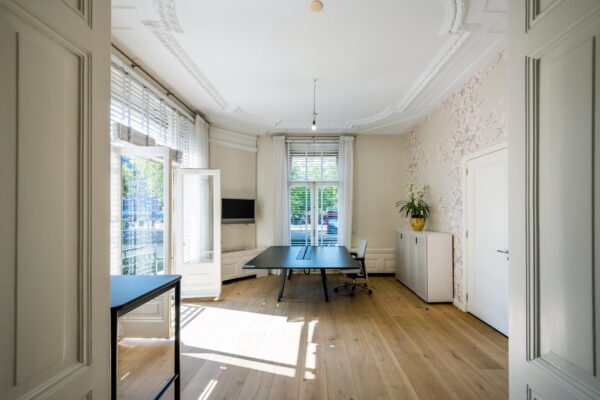Licht en ruim kantoor aan de Weteringschans met grote ramen, houten vloer en moderne inrichting.