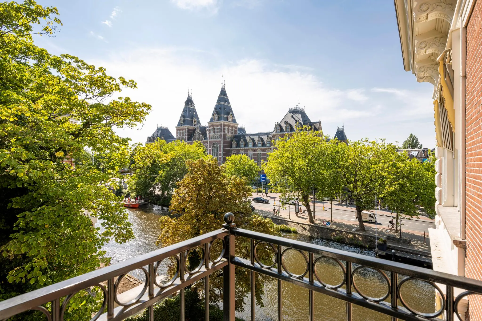 Uitzicht vanaf een balkon aan de Weteringschans op het Rijksmuseum en de gracht in Amsterdam op een zonnige dag.
