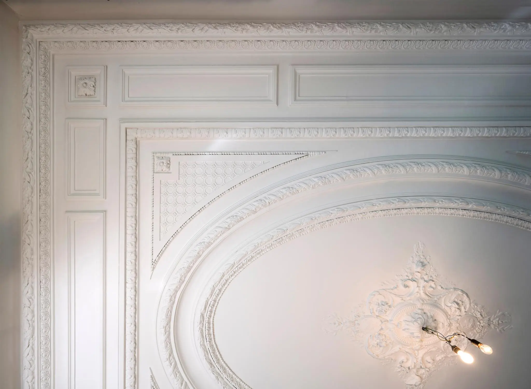 Plafond met sierlijke witte stucornamenten en een klassieke lichtarmatuur aan de Weteringschans.